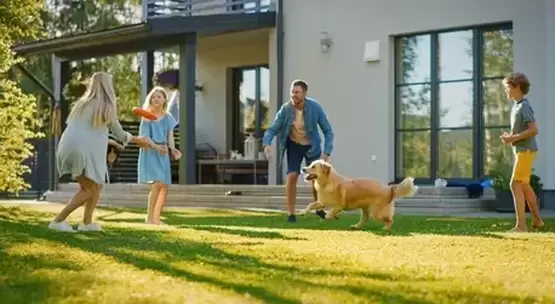 Family and dog playing together in their landscaped lawn